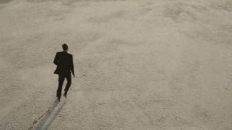A lone figure walking away across an empty desert