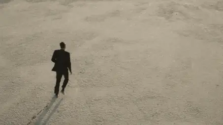 A lone figure walking away across an empty desert